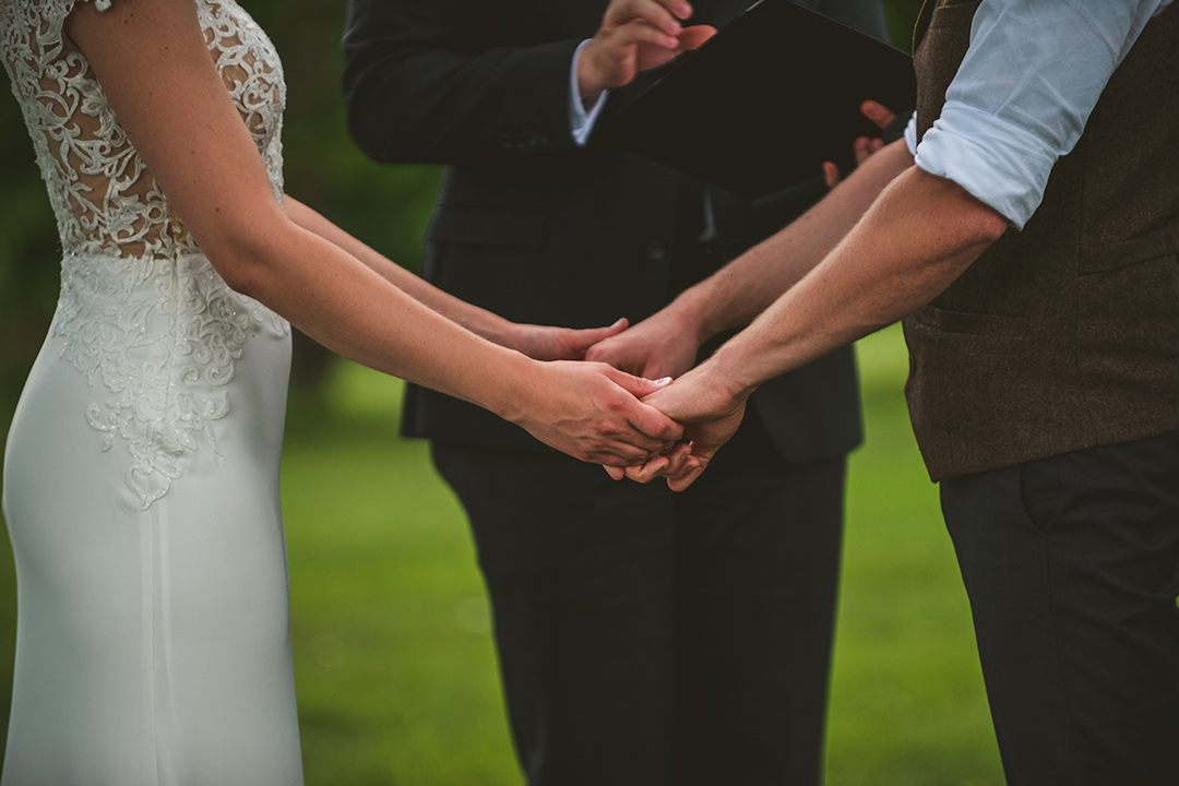 a close up of a bride and groom holding hands as they say their vows