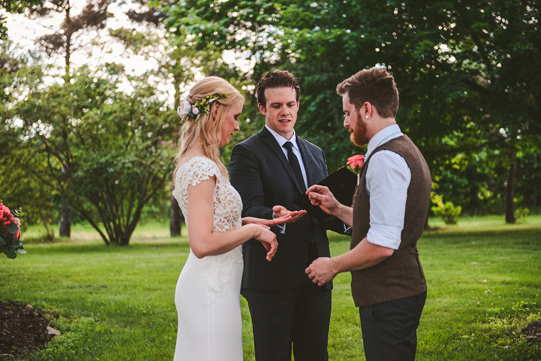 a groom taking his brides ring from the pastor at an apple orchard in Woodstock