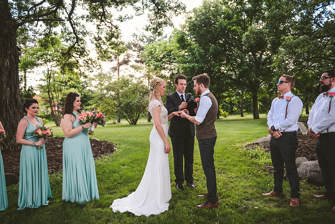 a groom putting a ring on his brides hand during their wedding at the All Season Orchard