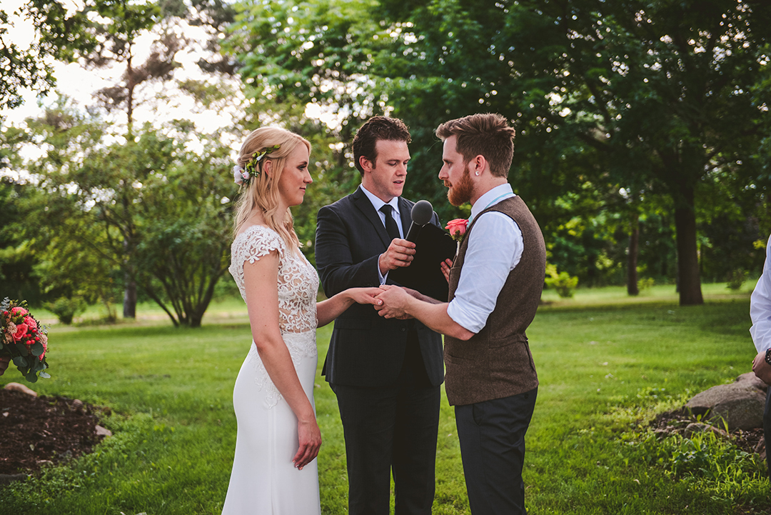 a groom holding his brides hand as they exchange vows at the All Season Orchard