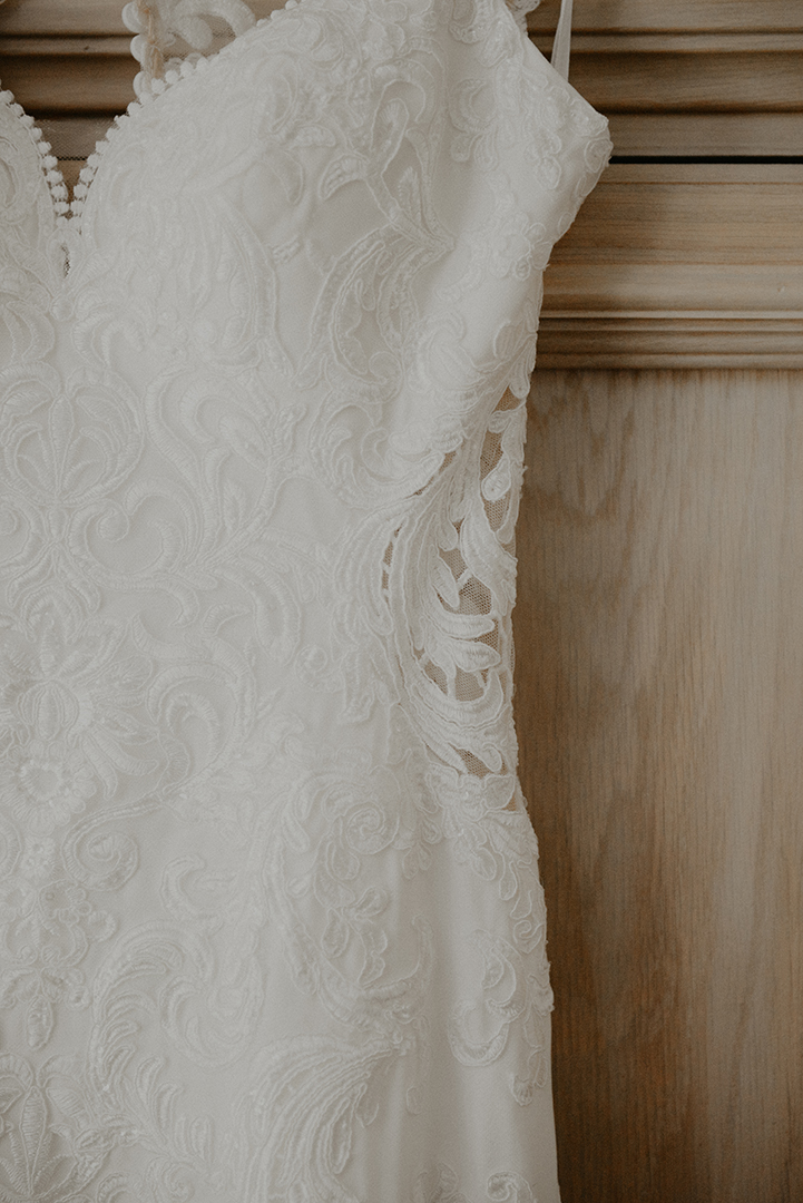 the brides dress hanging on a rustic cabinet