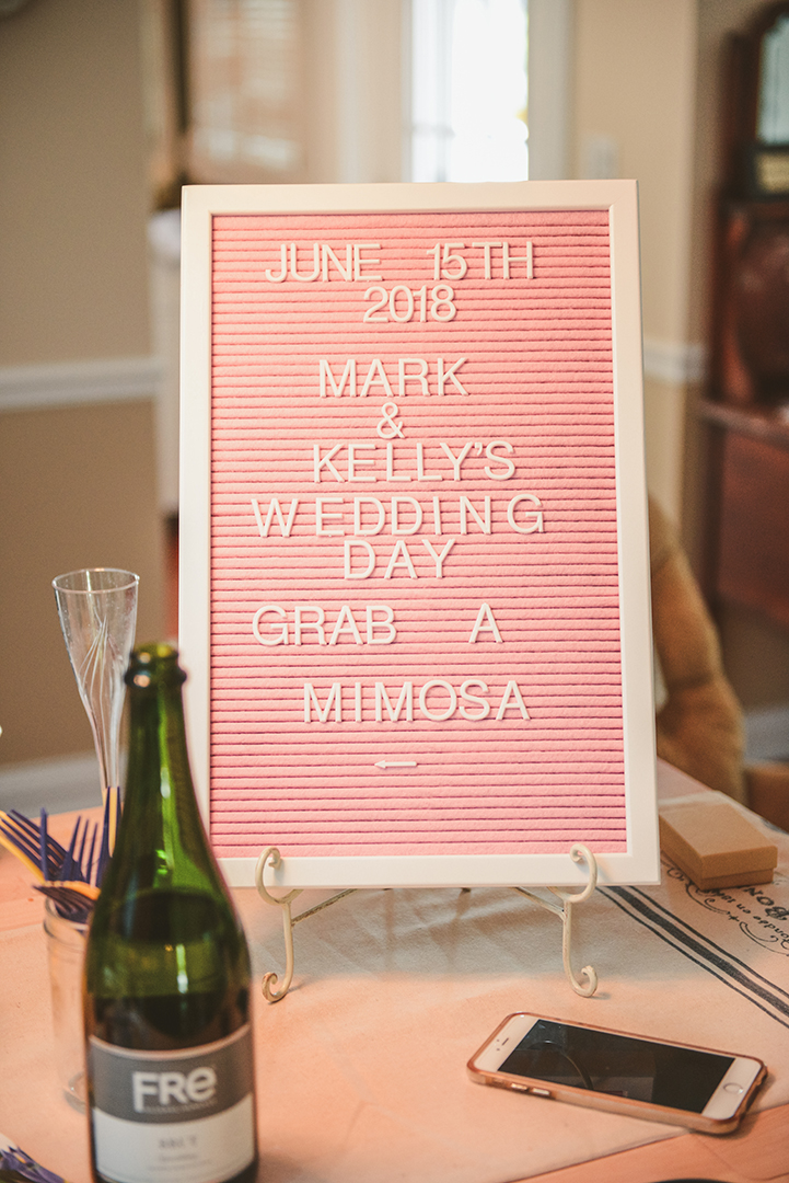 a sign with the date and mark and kelly's wedding day, grab a mimosa written on it