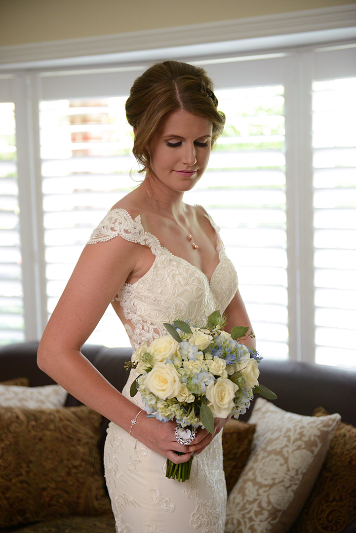 the bride looking down at her white and purple bouquet