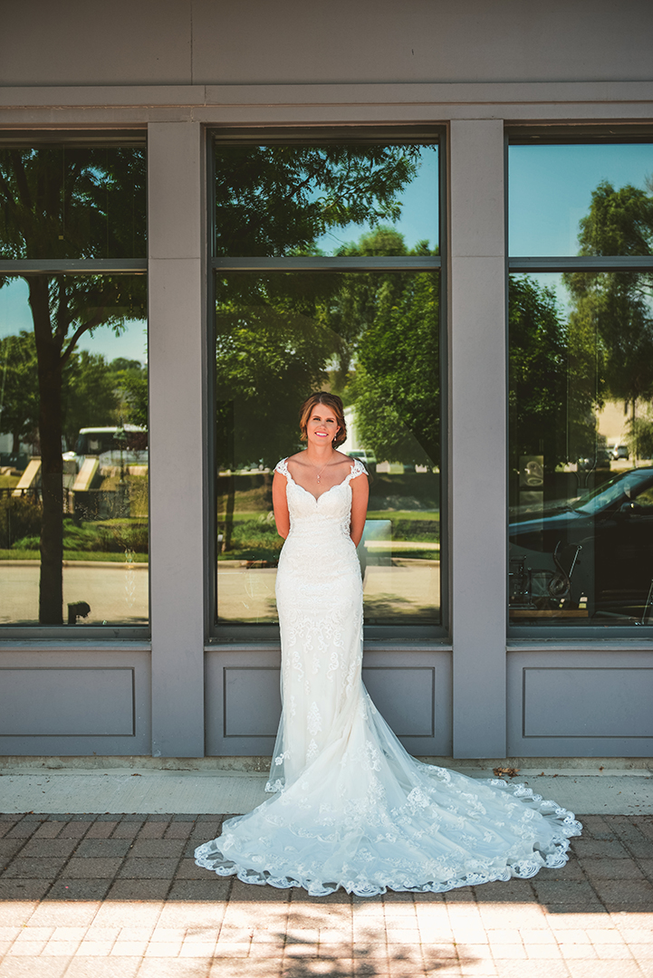 a bride standing in front of a bank of windows with her train in front of her