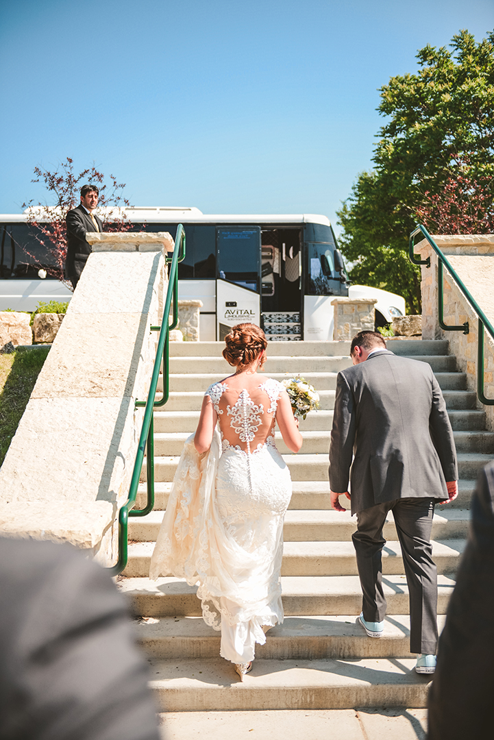 a bride and groom walking up steps towards their party bus