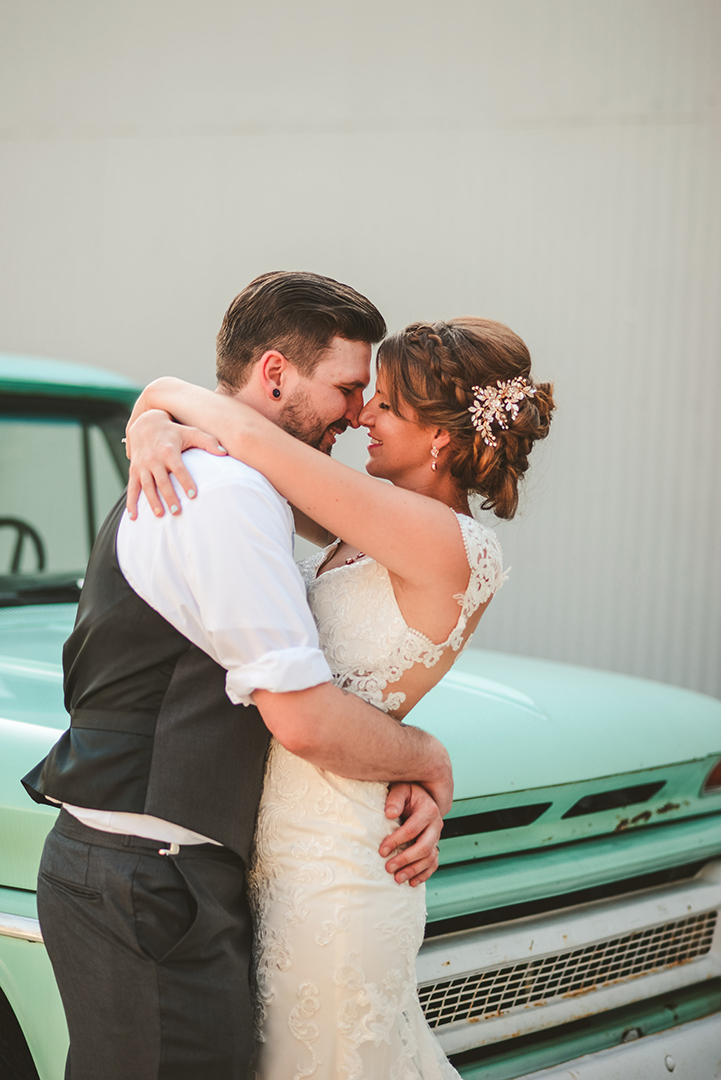 the bride and groom getting close in front of an old truck at Warehouse 109