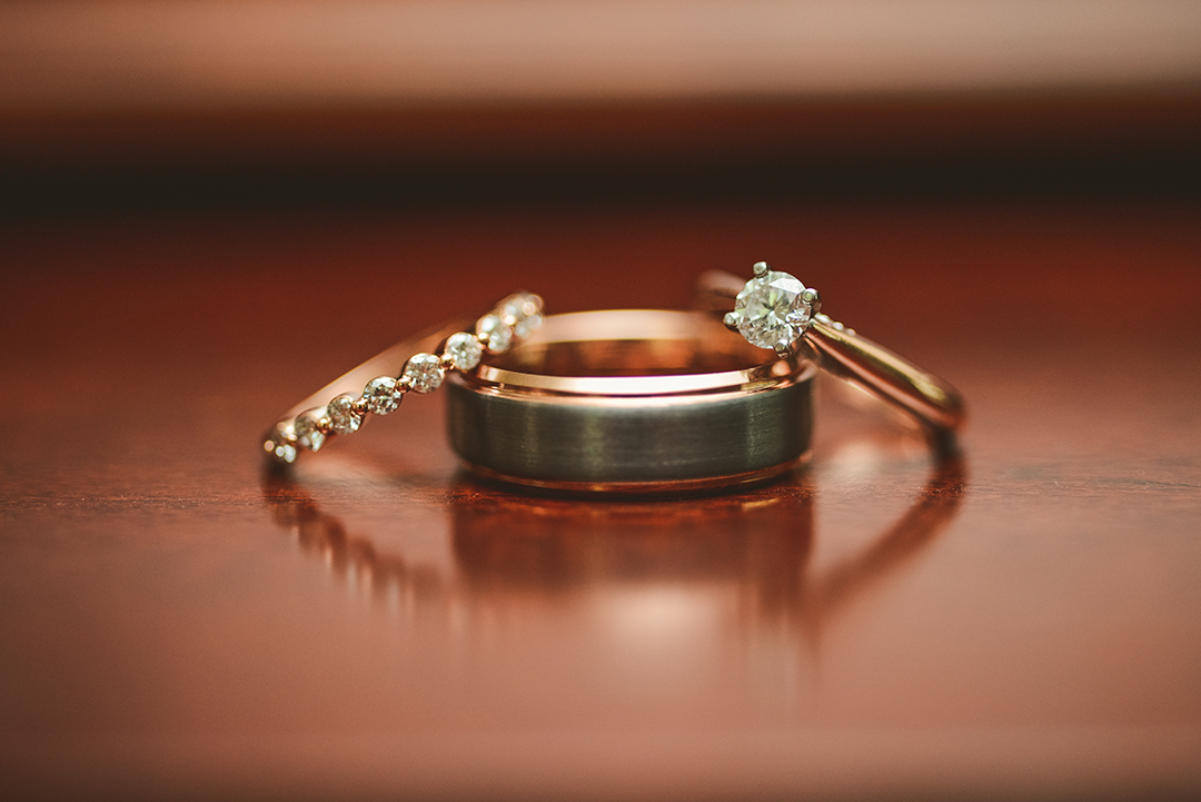 the bride and grooms rings on a wooden surface with a refection