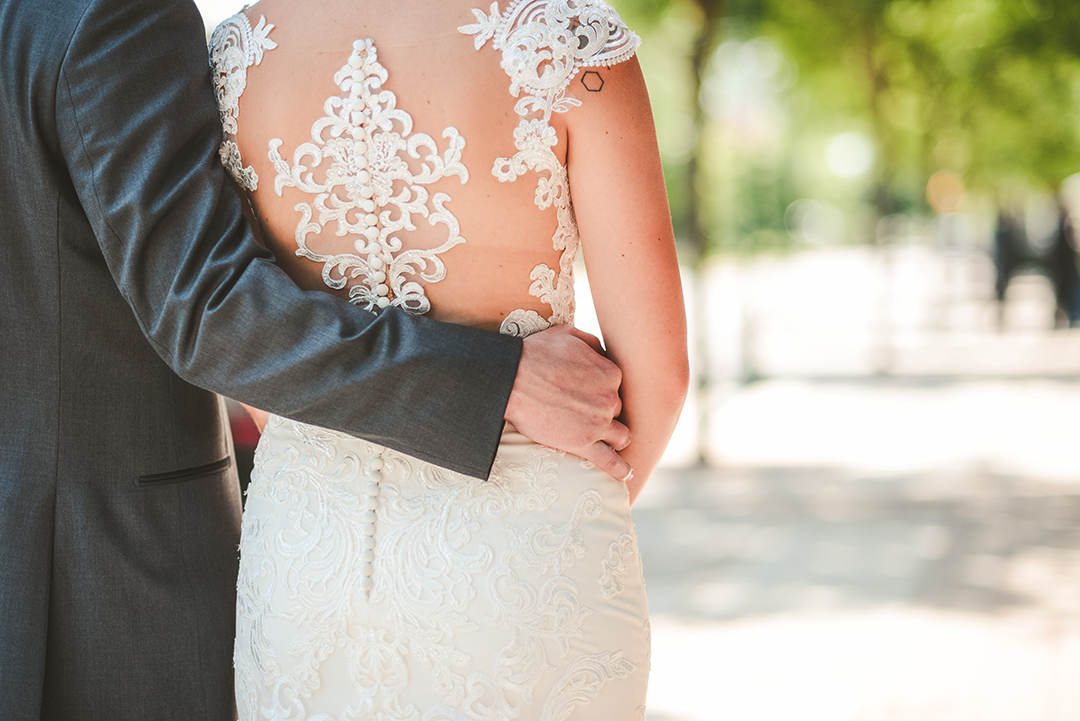 a grooms arm around his bride with her beautiful white dress