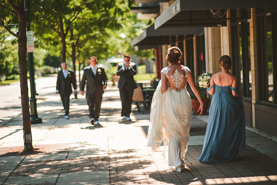 the bride walking away from the camera to a group of groomsmen