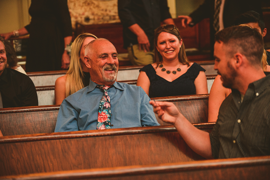 a wedding guest laughing as he talks with his friend