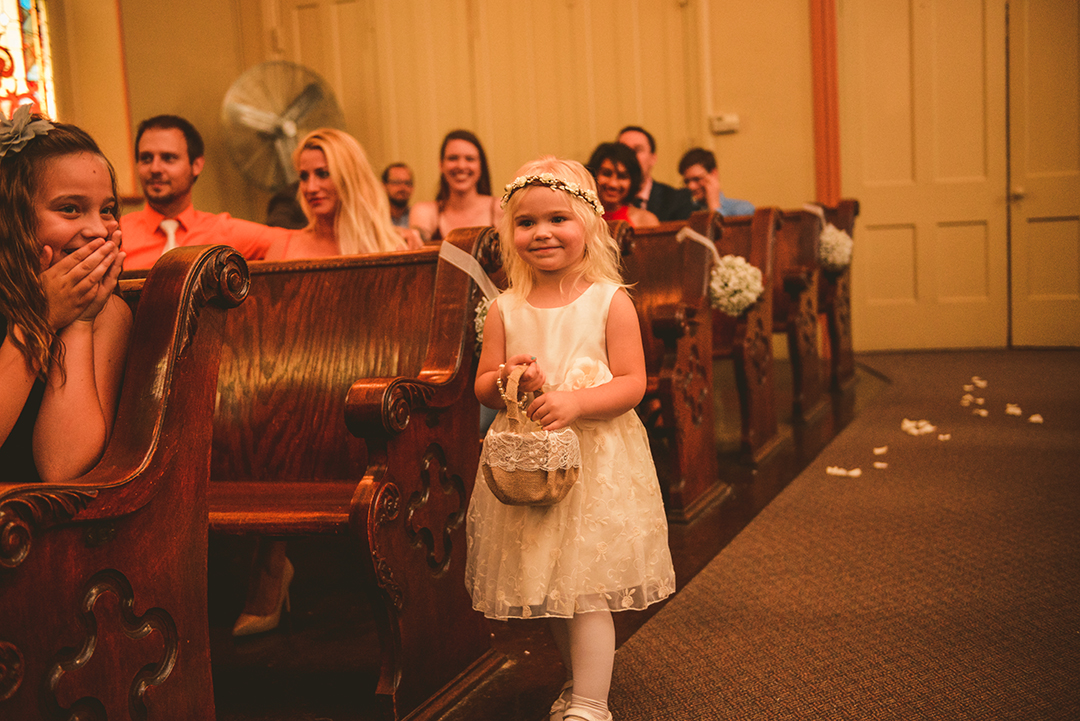 a flower girl walking down the aisle at a wedding ceremony at The Old Stone Church