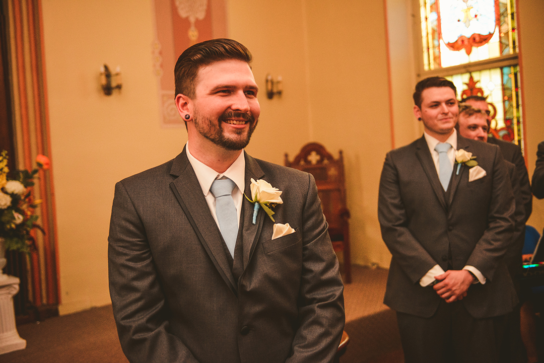 The groom smiling as he sees his bride coming down the aisle at The Old Stone Church