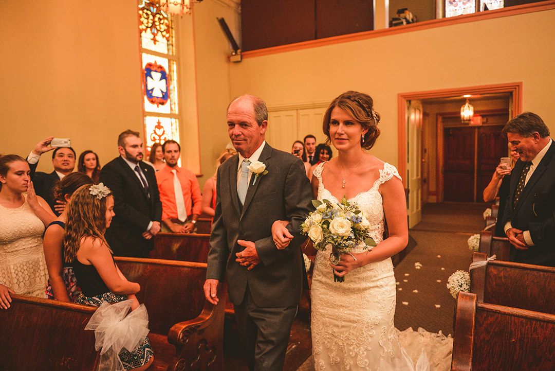 the bride and her father walking down the aisle of The Old Stone Church