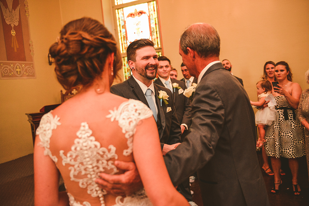 the groom shaking the brides fathers hand as he hands her off