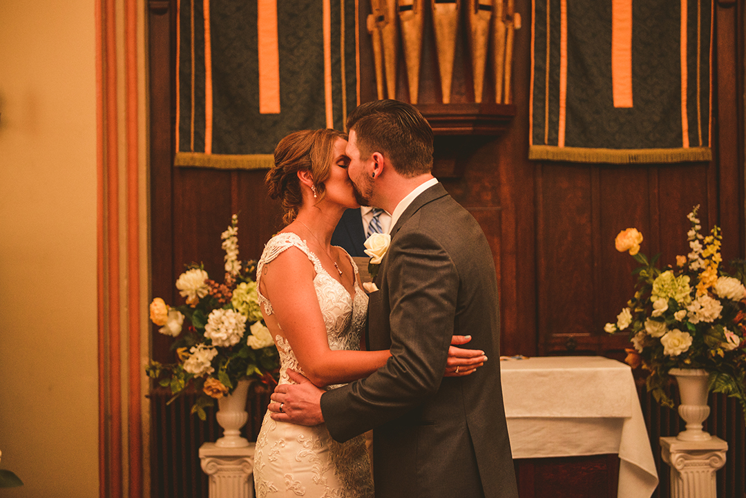 a bride and grooms first kiss at The Old Stone Church in Lemont