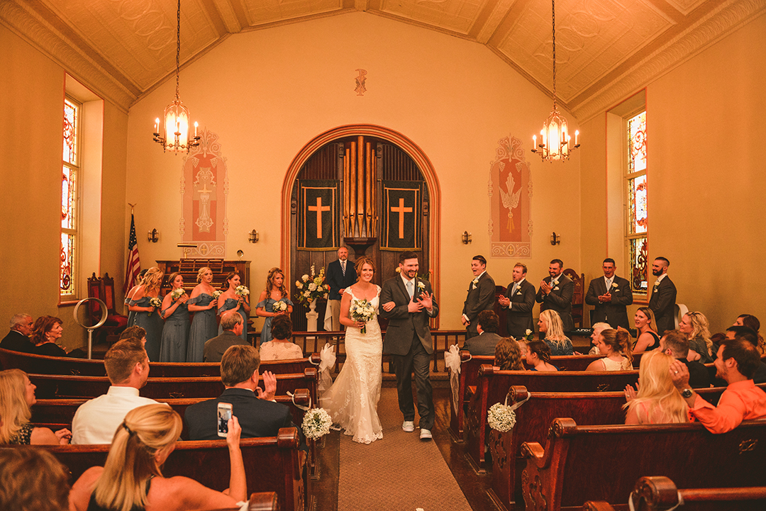 a bride and groom smiling as they walk down the aisle after getting married