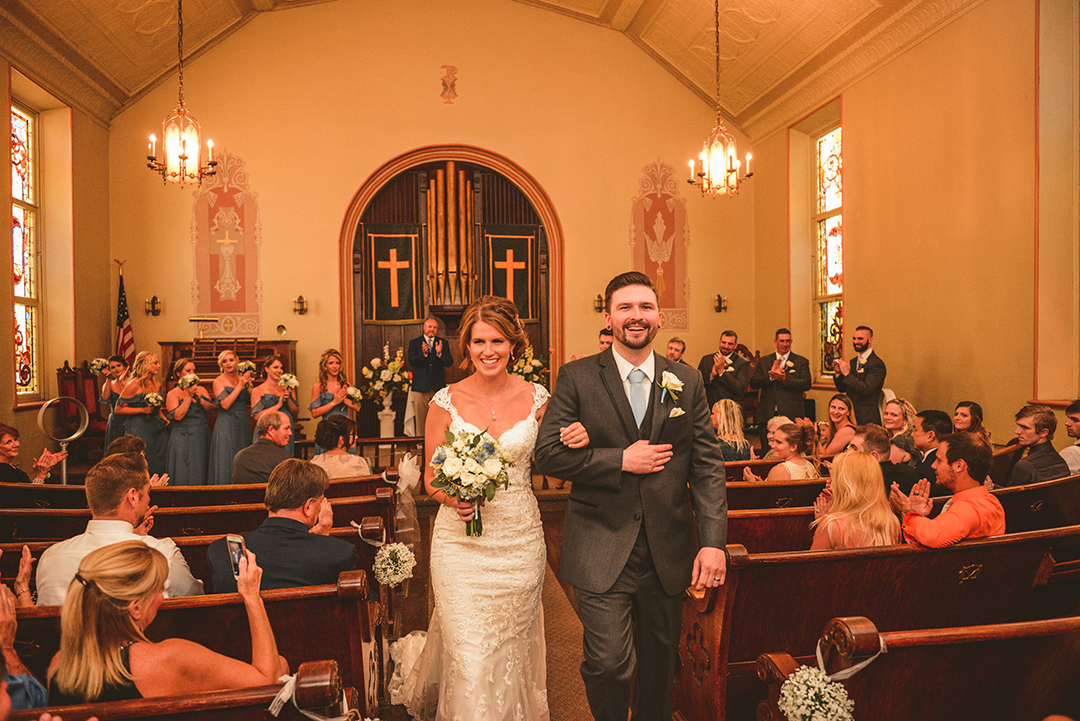 a bride and groom walking down the aisle after getting married at The Old Stone Church in Lemont