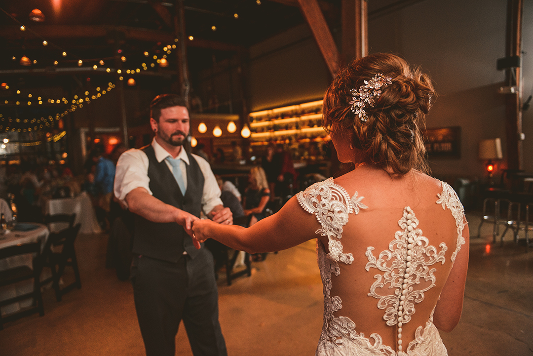 a bride and groom dancing during their first dance at a rustic wedding venue