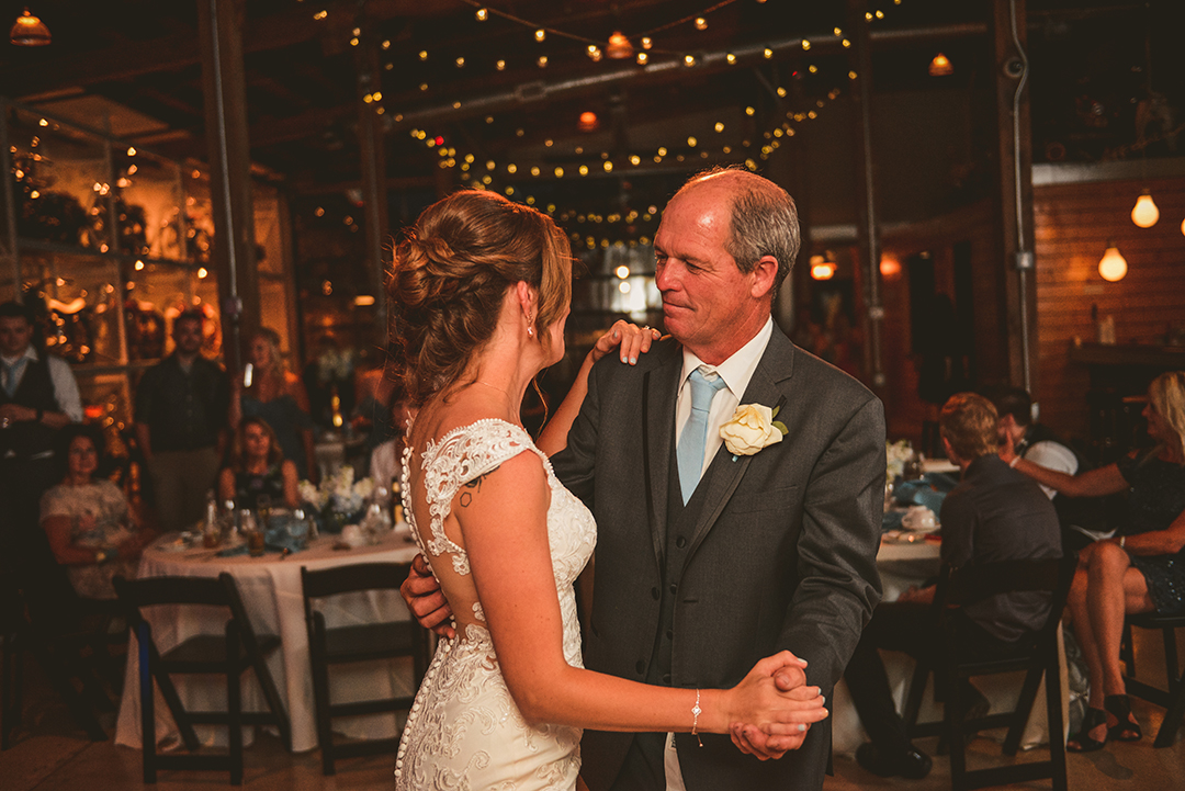 a father holding his daughters hand while dancing at a wedding reception