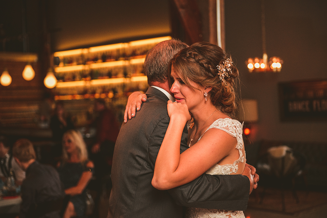 a bride crying as she dances with her father during the father daughter dance at Warehouse 109