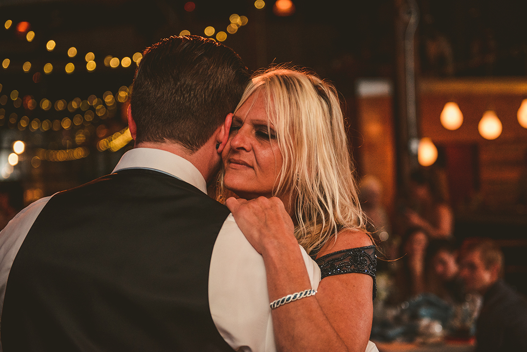 a mother getting close to her son during the mother son dance at a wedding reception