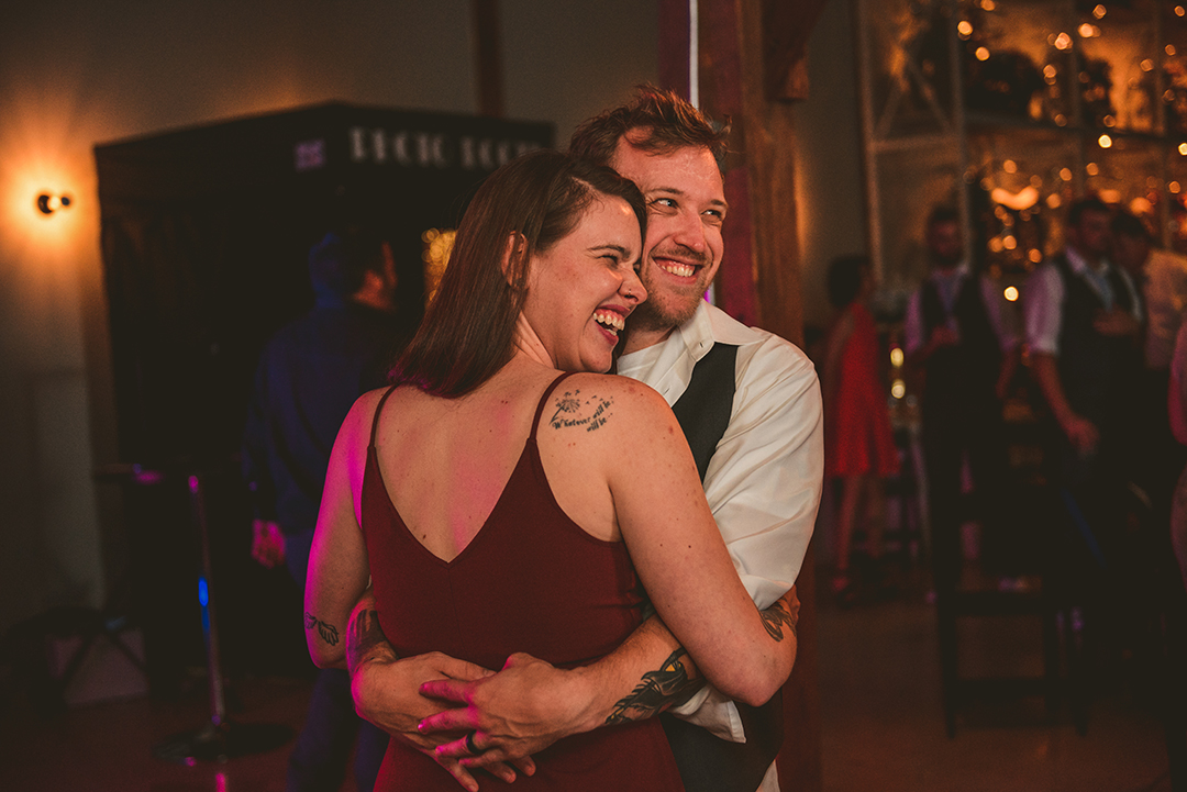 a husband and wife laughing as they dance together at a wedding reception