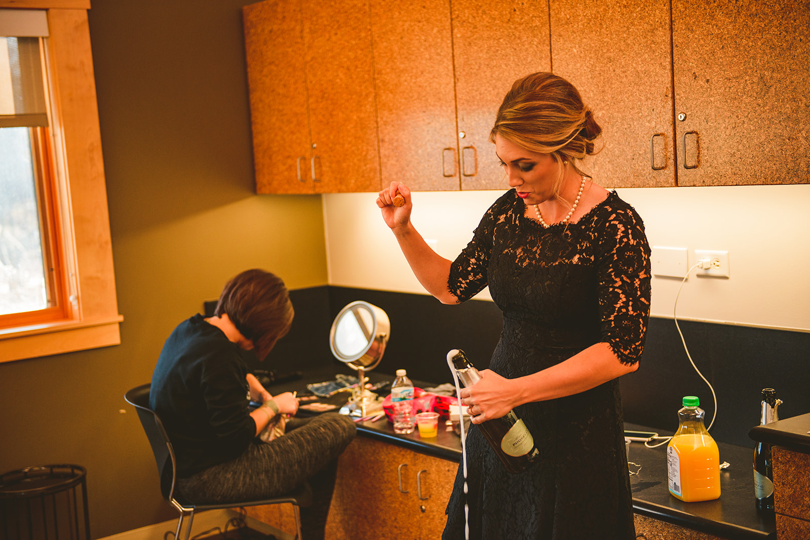 the maid of honor opening a bottle of champagne as it sprays out of the top of the bottle at the Four Rivers Environmental Education Center