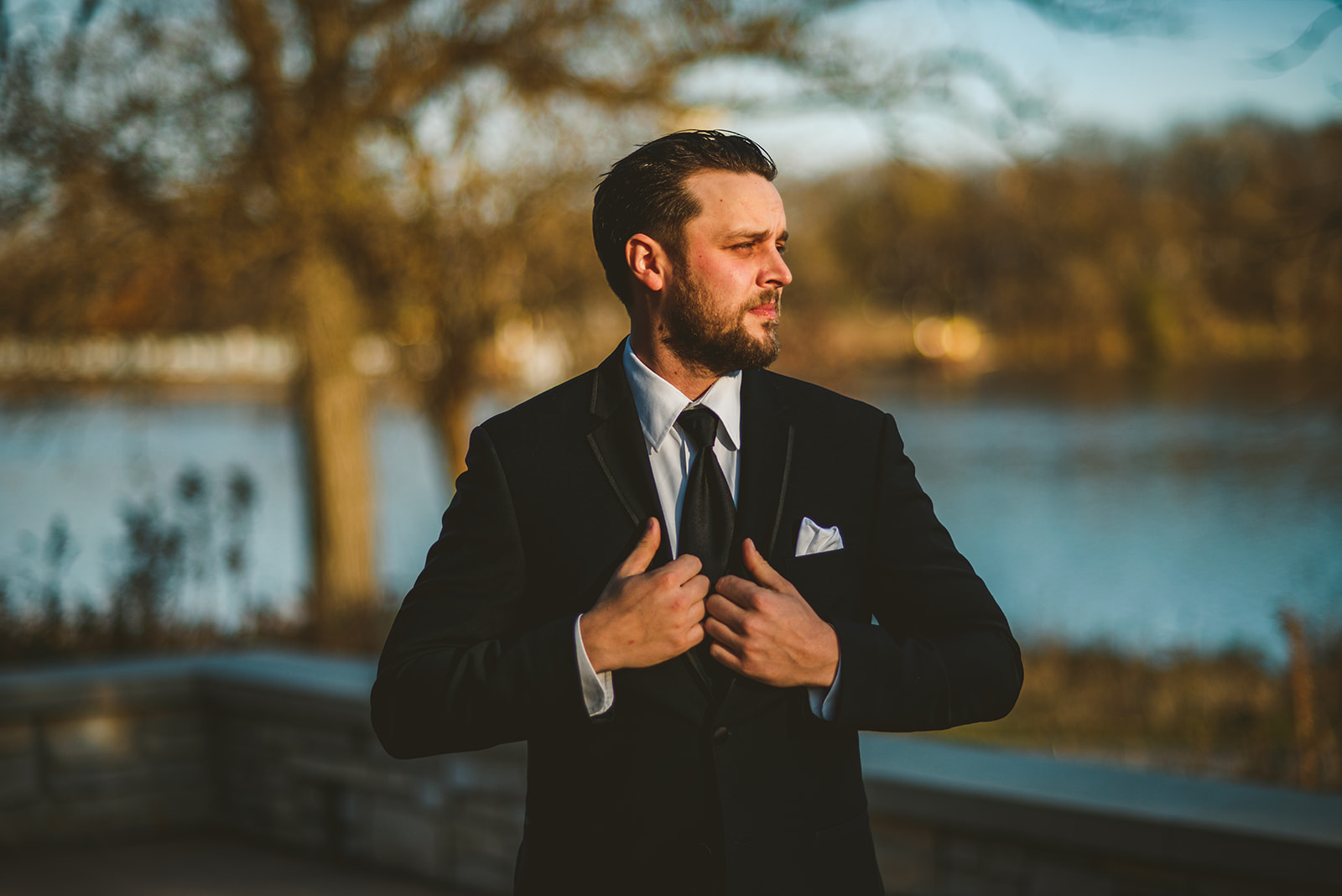 the groom adjusting jacket in the setting fall sun before his wedding