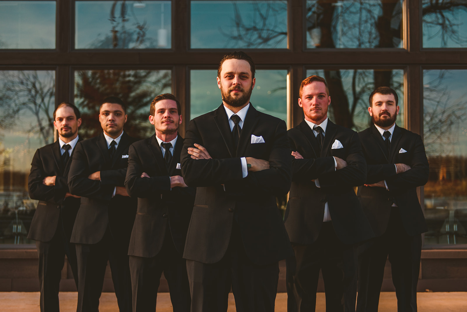 the groom and his groomsmen standing with their arms crossed looking at the camera