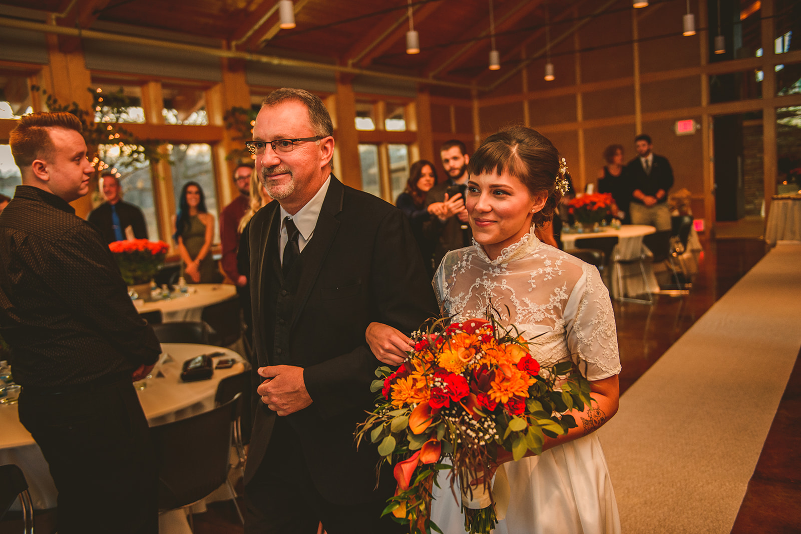 the bride smiling at her groom as her father walks her down the aisle at the Four Rivers Environmental Education Center in Channahon