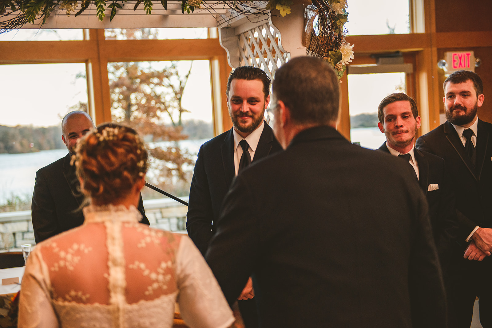 the groom watching as the brides father walks his daughter down the wedding aisle