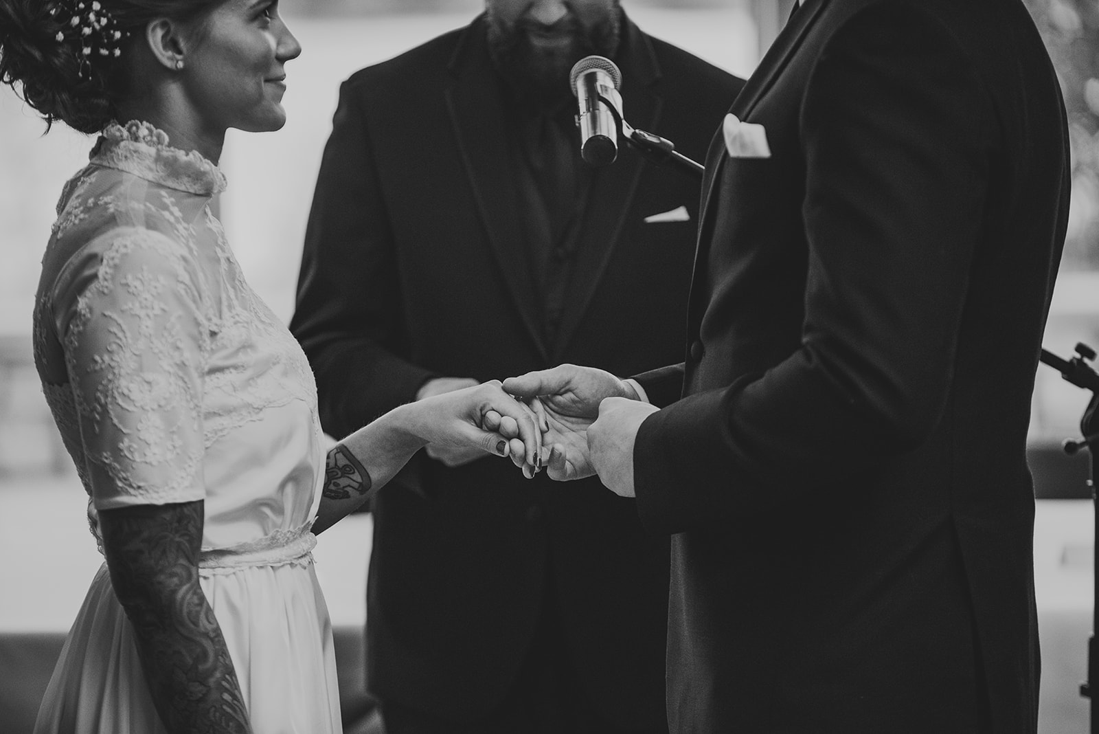 a black and white image of a groom putting a ring on his brides hand at the Four Rivers Environmental Education Center