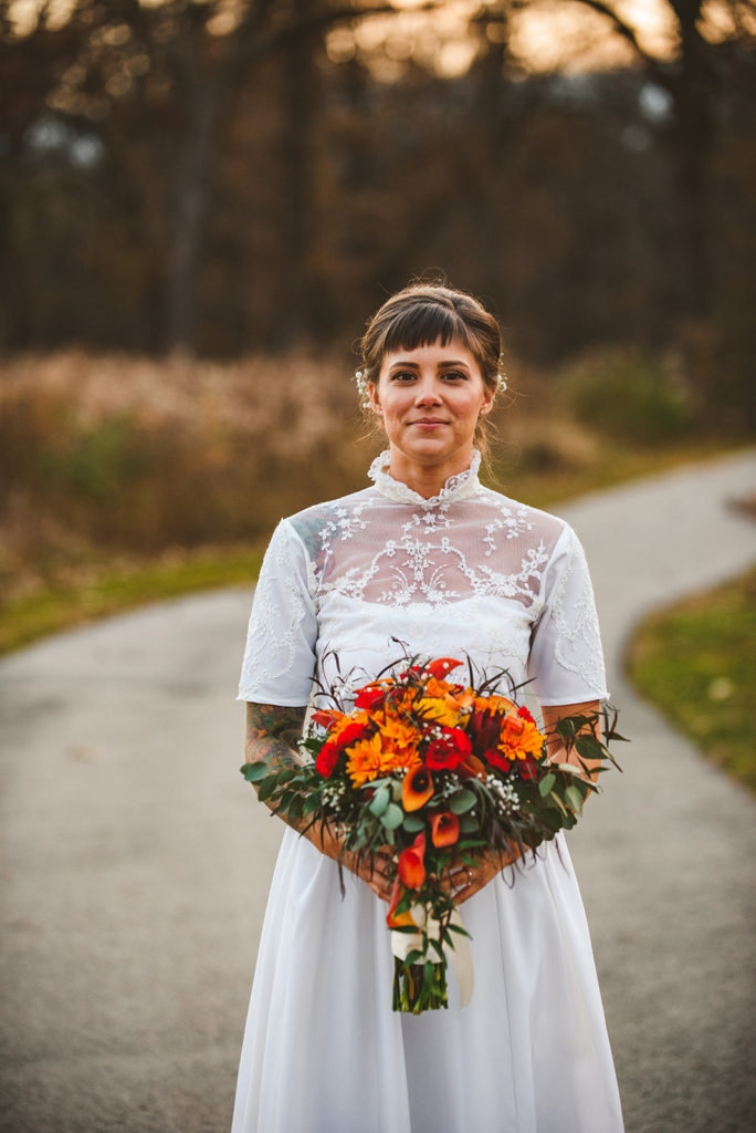 a bride holding her flowers while walking down a path in the late evening light of wall at the Four Rivers Environmental Education Center in Channahon