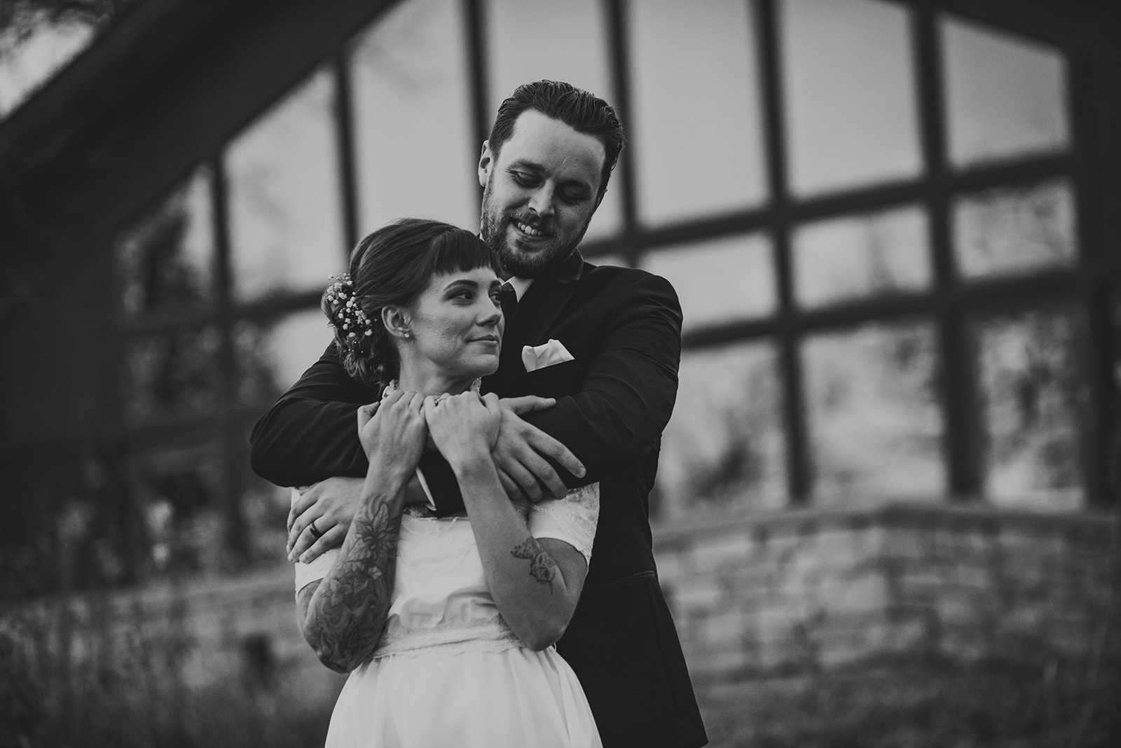 a groom with his arms around his bride as they stand in the cold weather air of fall at the Four Rivers Environmental Education Center