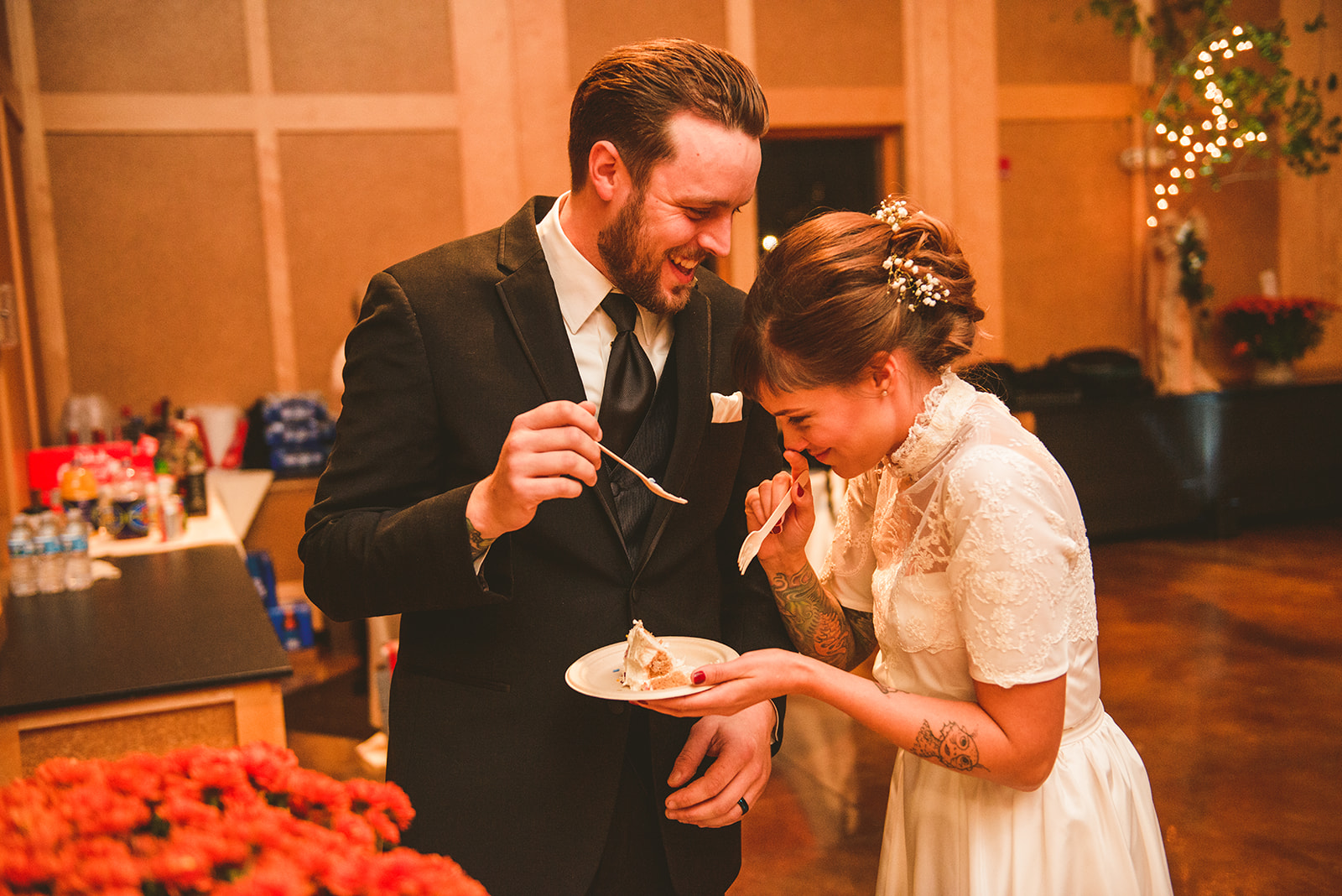 a bride laughing as her groom feeds her cake at the Four Rivers Environmental Education Center