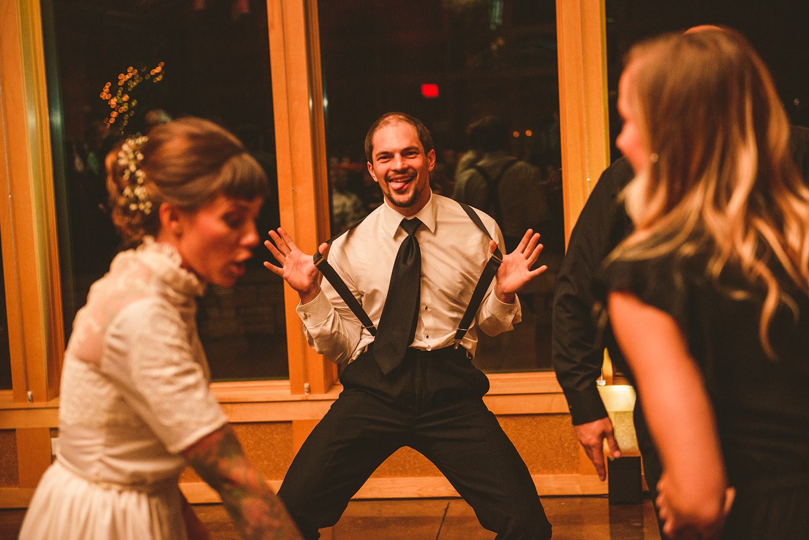 the best man flicking his suspenders as he makes a funny face at the camera