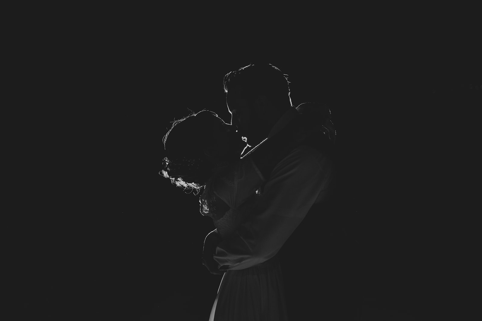 a husband and wife kissing at night silhouetted on the night sky at the Four Rivers Environmental Education Center