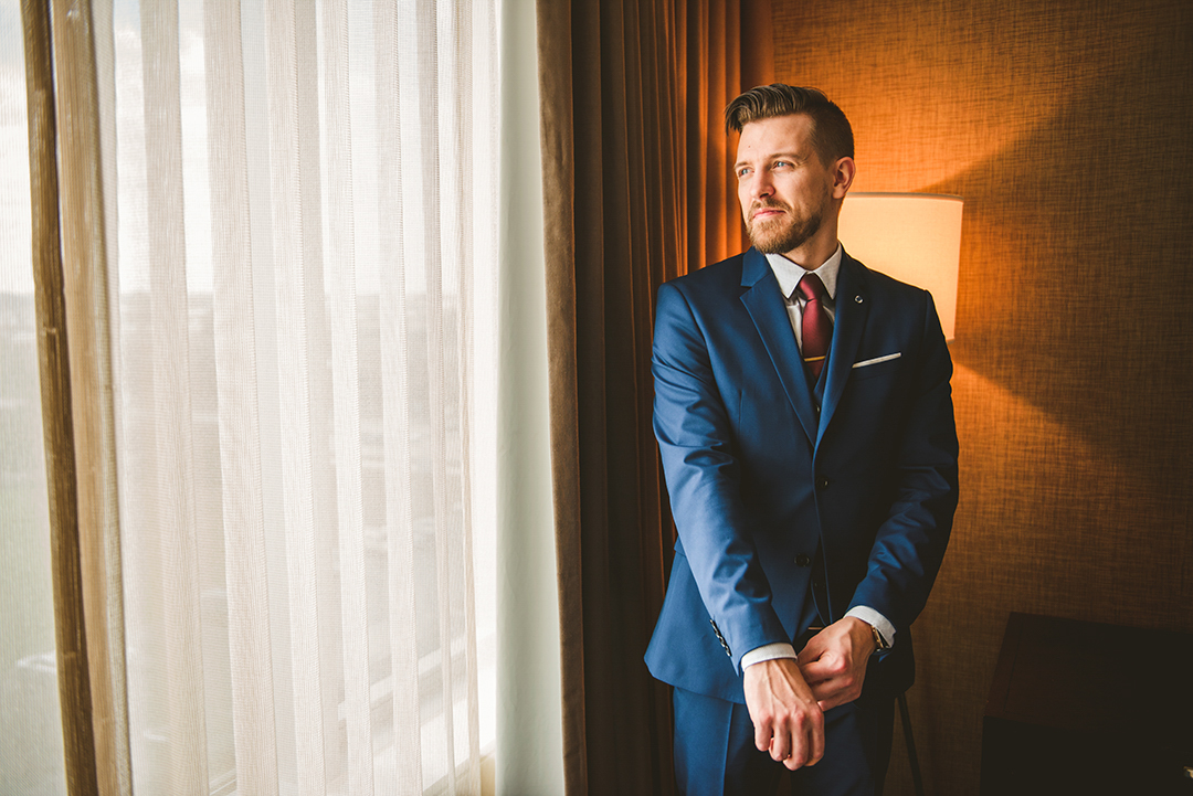 a groom getting ready for his wedding at the Hotel Arista in Naperville with beautiful golden light in the background