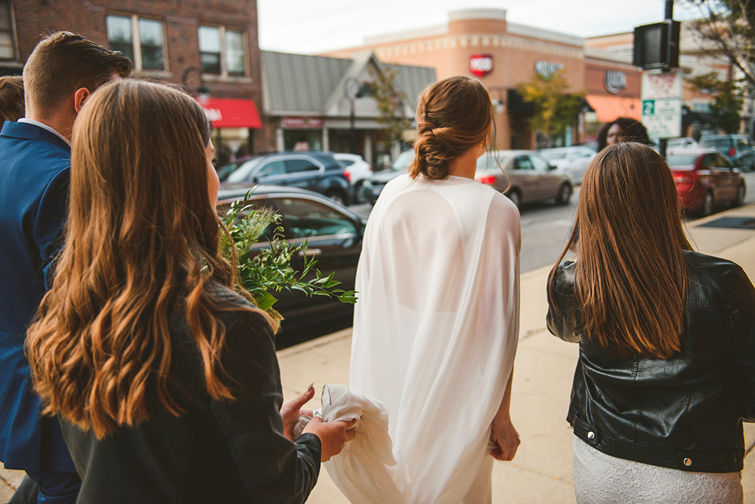 a bride and her guests walking around downtown Naperville as she walks back to her wedding reception