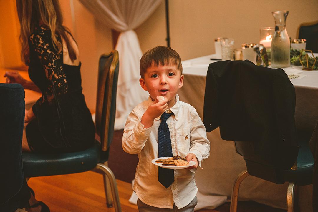 a little boy eating cookies with a messy face at a downtown Naperville wedding reception