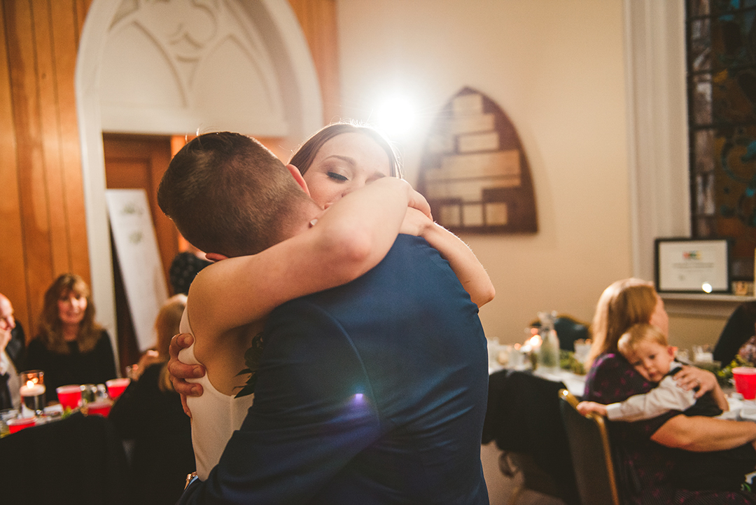 a bride hugging her groom as she dances her first dance in downtown Naperville