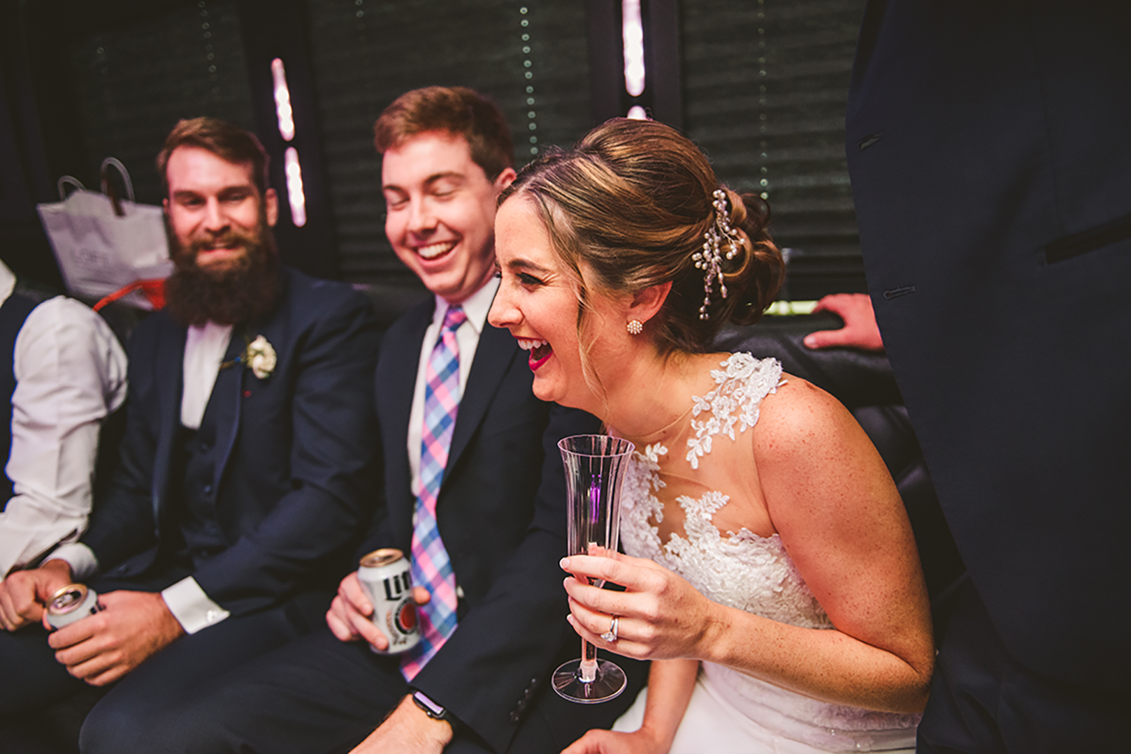 a bride laughing on a party bus at a Cantigny Park wedding while holding her glass