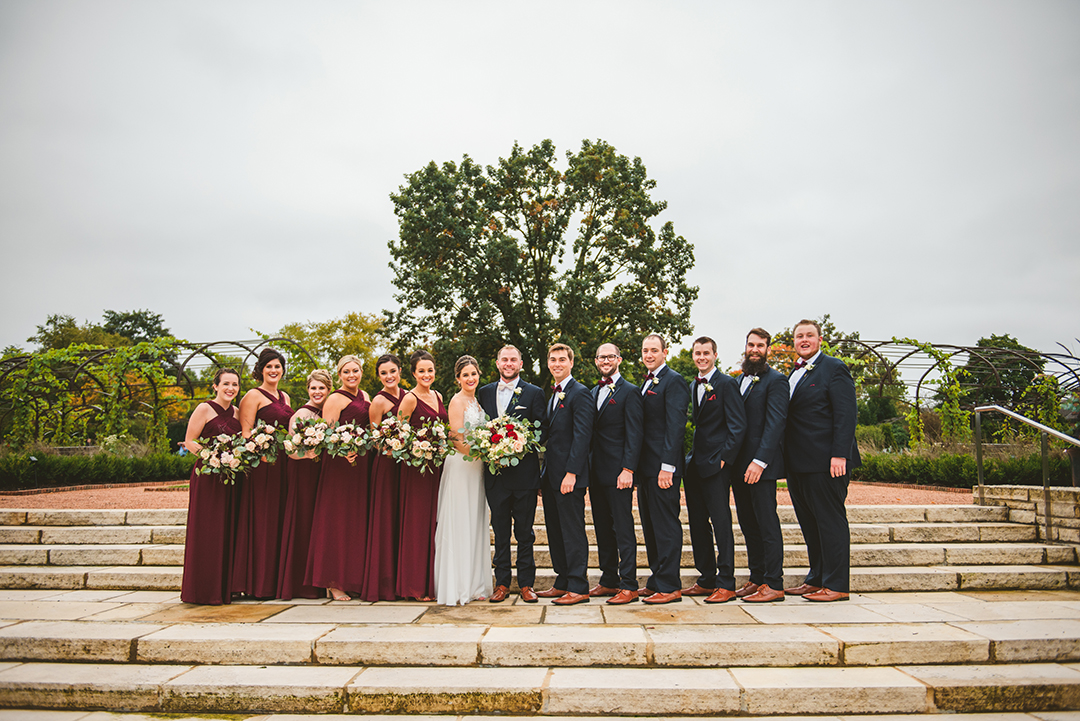 a bridal party standing on steps at a Cantigny Park wedding with a large oak tree in the background on a fall day