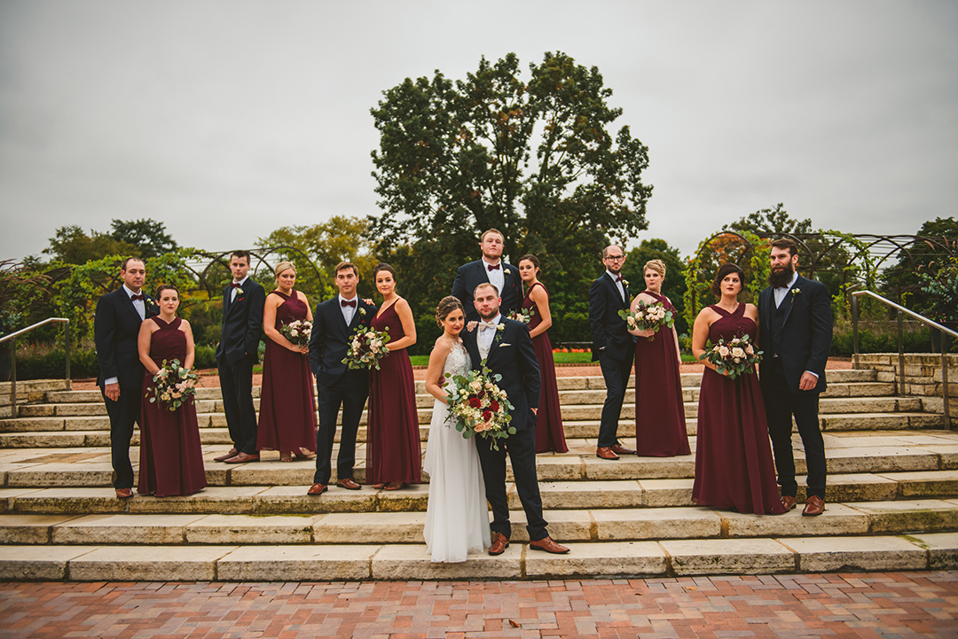 a moody photo of a bridal party standing on steps at a Cantigny Park wedding with a gloomy sky in the backgroun