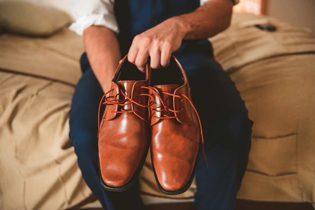 the groom holding his shoes as he gets ready for his wedding