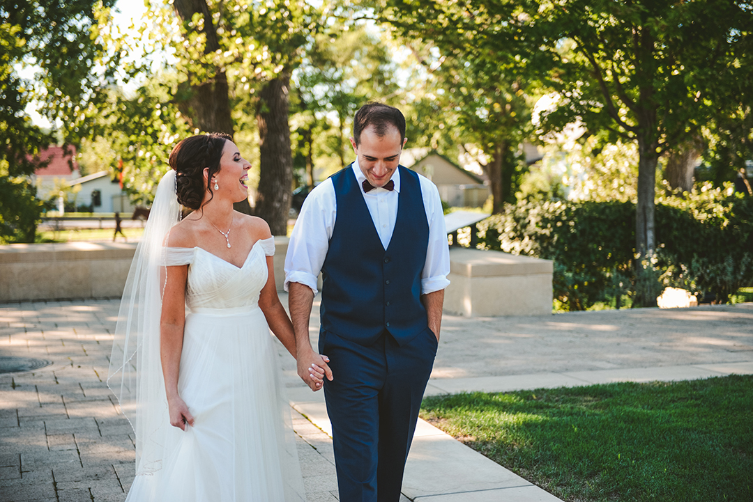 a bride and groom laughing as they walk through a park in Lockport before getting married