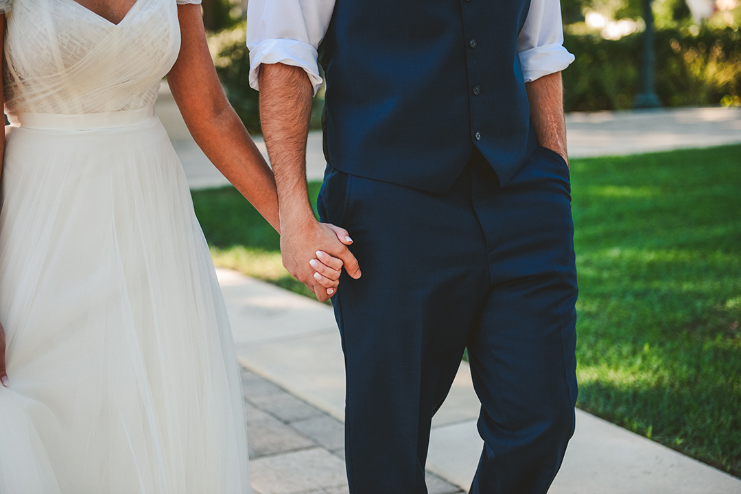 a bride and groom holding hands as they walk at a park in Lockport IL