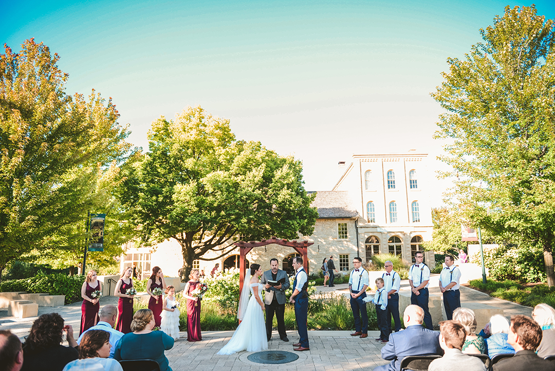 a bride and groom and their bridal party at the alter in a park in Lockport