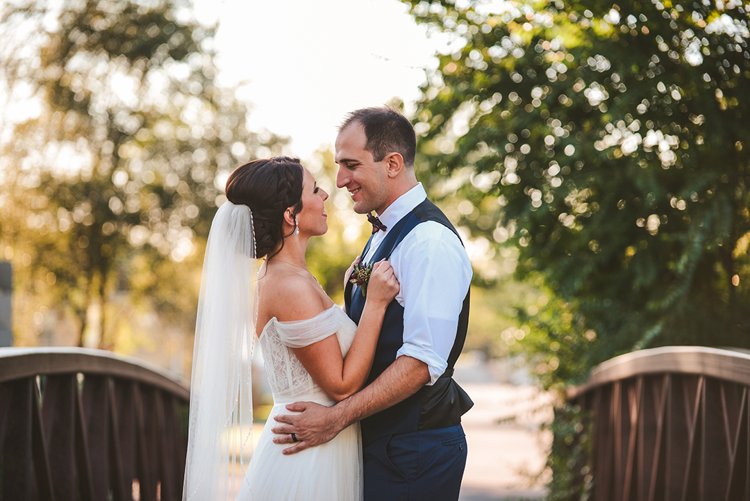 a bride and groom holding on to each other on a old bridge in Lockport during the evening