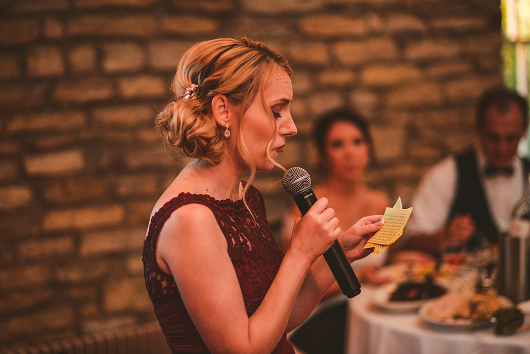 the maid of honor giving a speech as the bride and groom watch